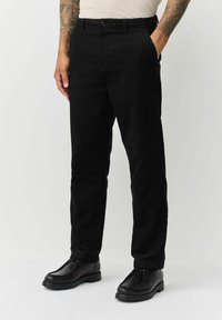 Black corduroy pants with a straight leg design, featuring a button closure and side pockets, paired with black shoes.