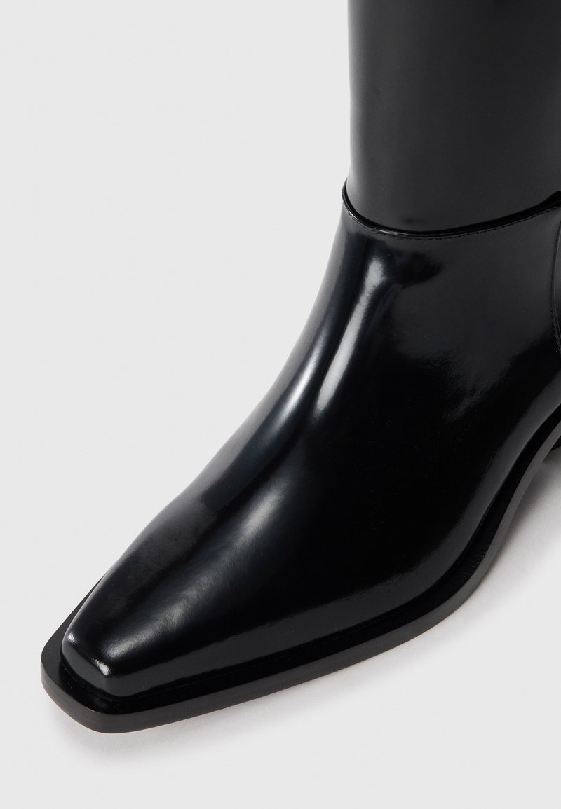 Schwarze Leder-Stiefelette mit spitzer Zehenform, eleganter Oberfläche und minimalen Nähdetails. Glatte Textur und robustes Absatzdesign.