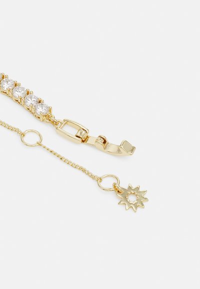 Bracciale in oro con cinque pietre preziose trasparenti incastonate in un design a catena. Include una chiusura e una catenina con un ciondolo a forma di sole.