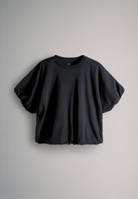 Sort t-shirt med korte ærmer, rund halsudskæring og en let rynket kant, vist mod en ensartet lys grå baggrund.