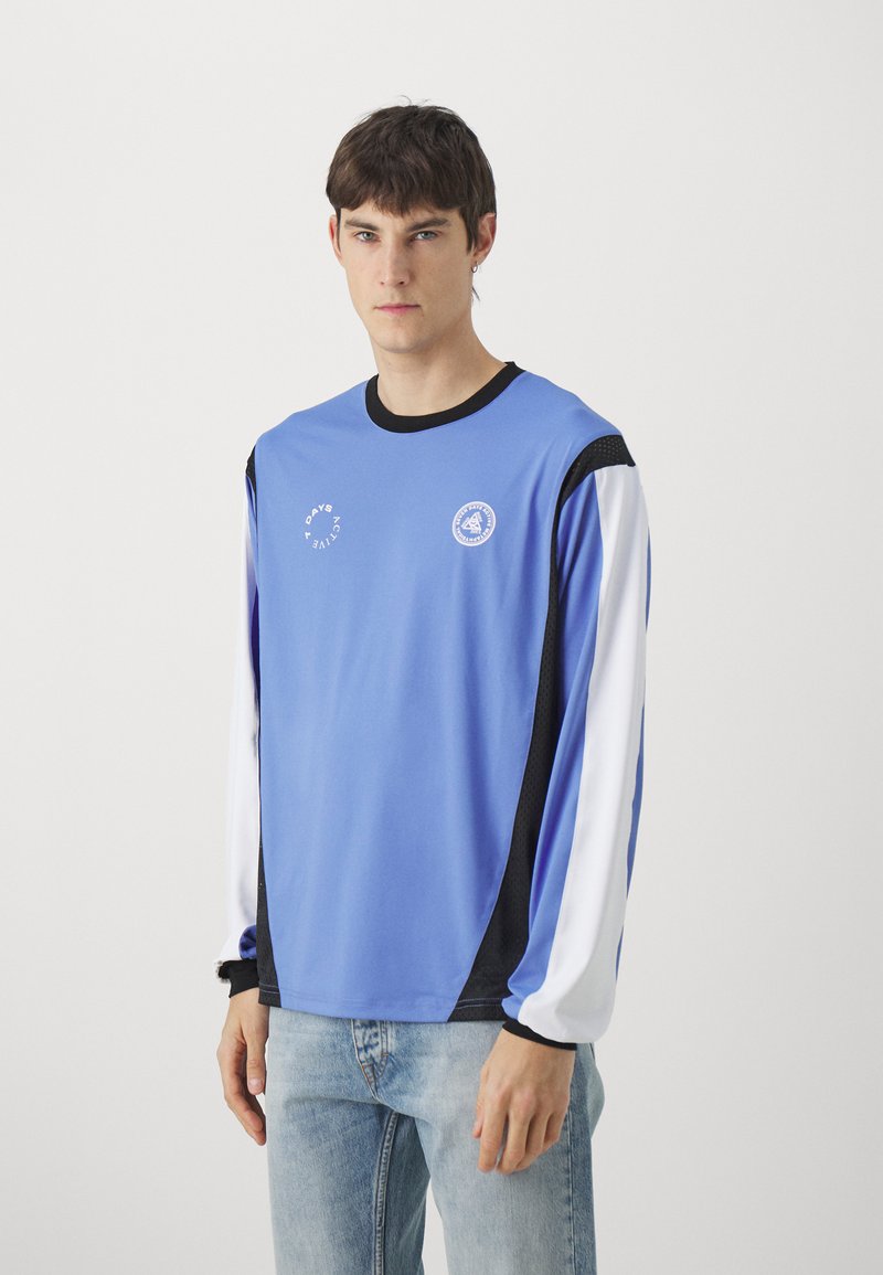 Light blue long-sleeve shirt with black accents, features white sleeves and a logo on the chest. Made of smooth fabric, relaxed fit.
