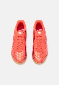 Tênis sintéticos vermelhos com parte superior texturizada, sola de borracha e fecho de atacadores. Apresentam um acabamento brilhante e a marca Nike na língua e na lateral.