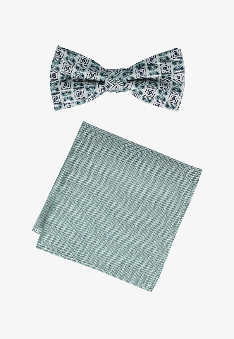 Eine Fliege mit einem bunten geometrischen Muster in Grün und Marineblau auf einem hellen Hintergrund, kombiniert mit einem strukturierten, einfarbigen mintgrünen Taschentuch.