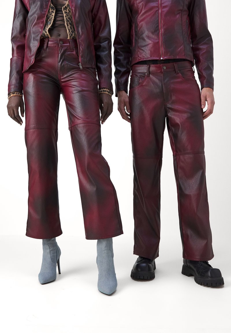 Deux personnes portent des vestes et des pantalons en cuir bourgogne assortis. Les pantalons ont une coupe décontractée avec une texture contrastée. Les chaussures varient en style.