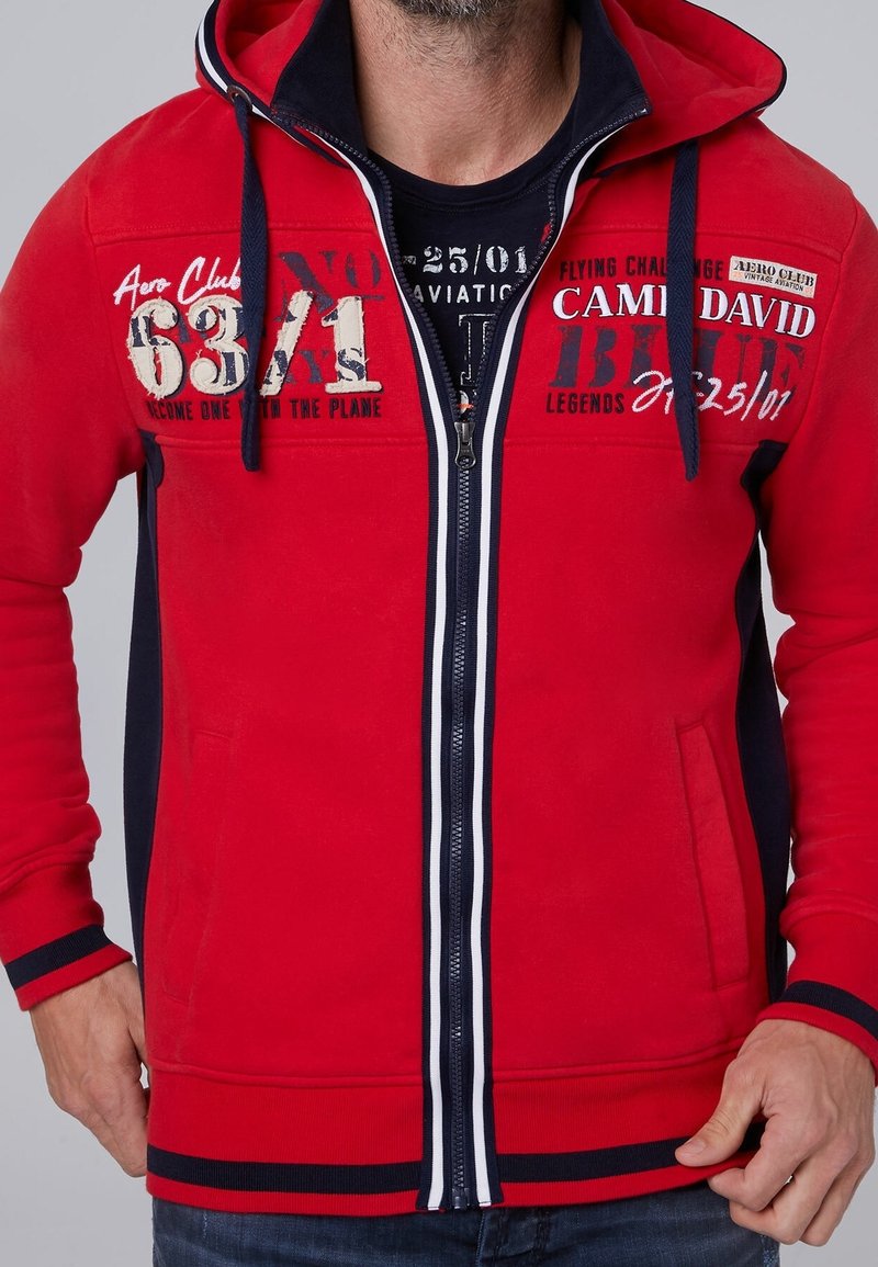Rode zip-up hoodie met marineblauwe accenten, voorzien van geprinte luchtvaartgraphics, een grote capuchon en ribgebreide manchetten en zoom. Soepele textuur, casual pasvorm.
