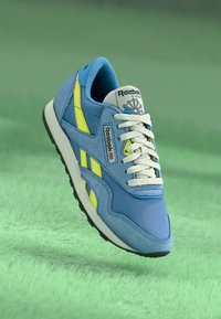 Μπλε και κίτρινο αθλητικό παπούτσι Reebok με άνω μέρος από διχτυωτό και σουέτ υλικό, λευκές κορδόνες, καουτσούκ σόλα και εμφανές λογότυπο στην γλώσσα.