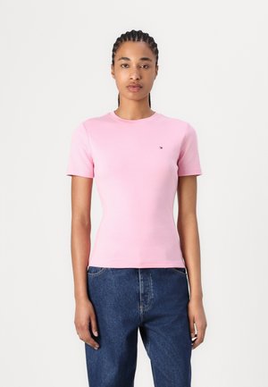 Roze T-shirt met korte mouwen van katoen met een ronde hals en een klein geborduurd logo op de borst, gecombineerd met blauwe spijkerbroek.