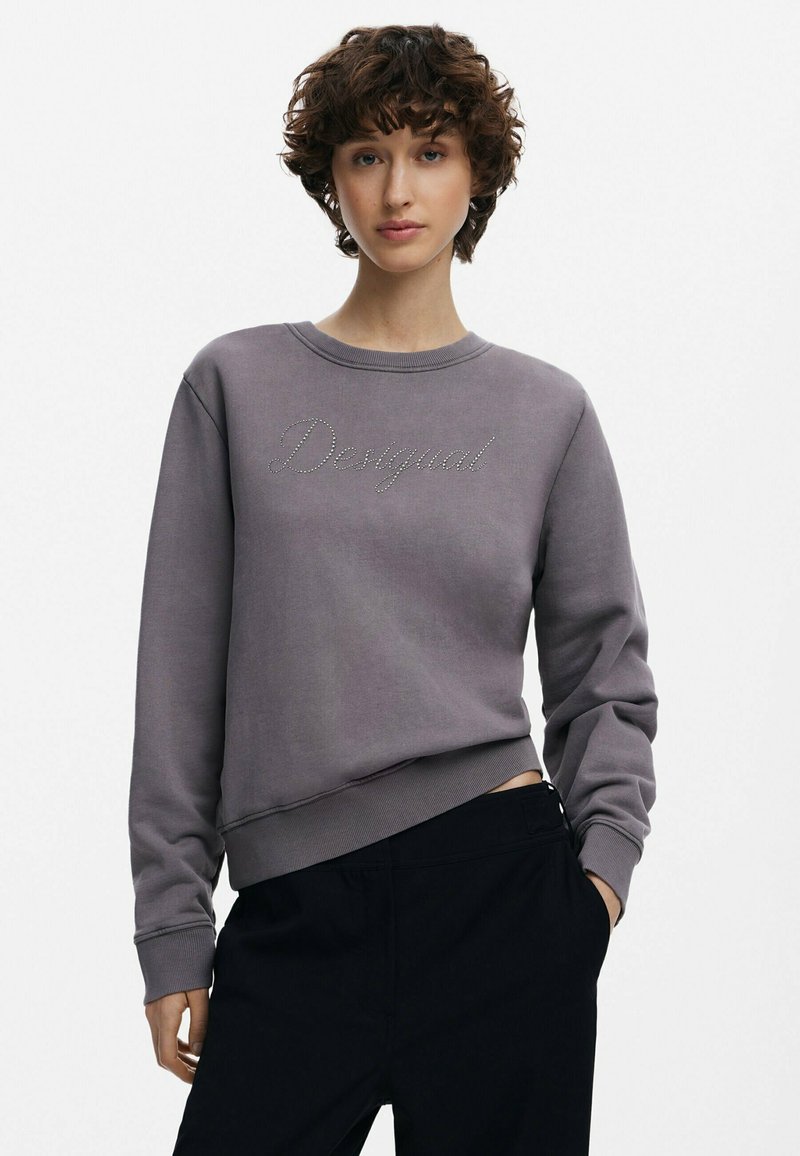 Hallide halliline dressipluus ümmarguse kaelusega, ribatud varruka- ja alumise servaga. Ees on "Desigual" teemanditest. Kombineeritud tumedate pükstega.