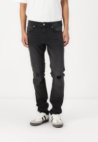 Sorte denimbukser med rett passform, med slitte detaljer og frontlommer. Kombinert med hvite og grå joggesko.