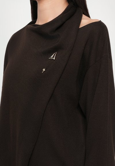 Brown knit top with a draped neckline, featuring gold hardware accents, including a triangular brooch and a pin on the front.