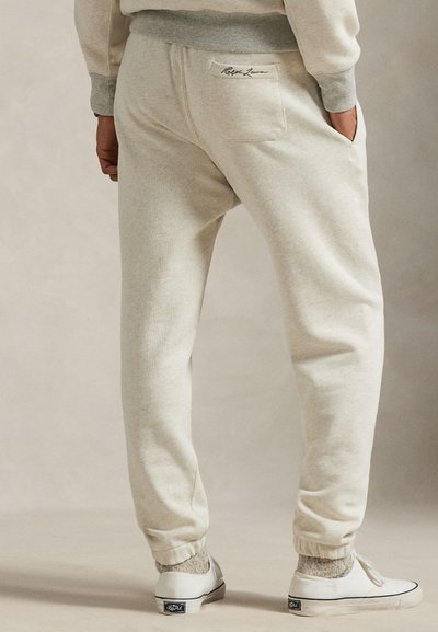 Lyse beige joggebukser i et mykt stoff med en avslappet passform, elastiske mansjetter og en liten logo på baklommen.