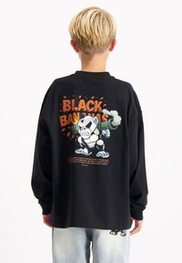 Zwart lang mouw shirt gemaakt van katoen met een grafisch ontwerp van een cartoonpanda en de tekst "BLACK PANDAS" met explosie-accenten.