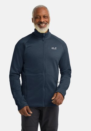 Marineblaues Fleecejacke mit hohem Kragen, Reißverschlusstaschen und Logo auf der Brust. Sie zeichnet sich durch eine glatte Textur und eine taillierte Passform aus, die für den Einsatz im Freien geeignet ist.
