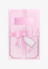 Pink Brush Works Beauty Countdown Adventskalender-Box, eingewickelt mit einem pinken Band und einem leeren Geschenkanhänger.