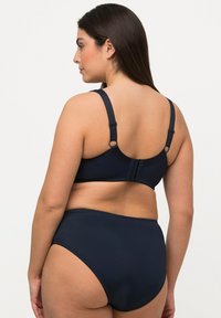 Bikini bleu marine au toucher lisse. Il présente des bretelles réglables, une fermeture à crochet et une culotte taille haute pour une couverture complète.