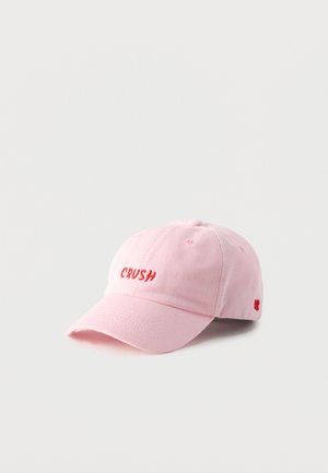 Light pink baseball cap with curved brim and red embroidered word "CRUSH" on front panel.