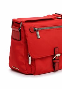 Czerwona nylonowa torebka na ramię z klapką zapinaną na klamrę, srebrnymi detalami zamka błyskawicznego oraz teksturowaną powierzchnią. Posiada regulowany pasek i akcent z logo.