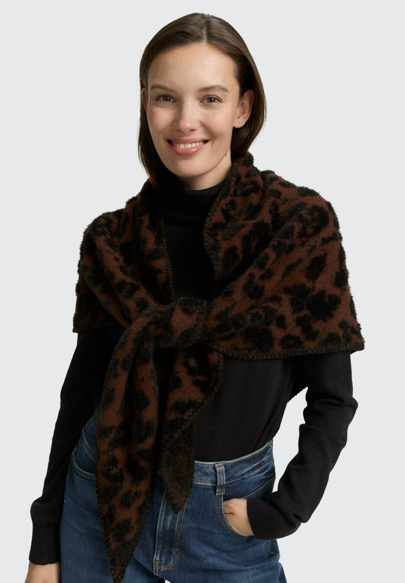 Châle en imprimé animal marron et noir, fabriqué en tissu doux et texturé, drapé sur les épaules, avec des extrémités pointues et une finition moelleuse.
