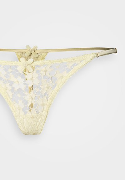 Κίτρινο δαντελωτό στρινγκ με λουλουδάτα σχέδια, διάφανο σχέδιο και σατινένιες λεπτομέρειες στη ζώνη μέσης. Λεπτή διακοσμητική ραφή κατά μήκος των άκρων.