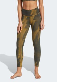 High-waisted leggings in olive green with yellow and dark patterns. Ribbed texture with seamless design for comfort and flexibility.