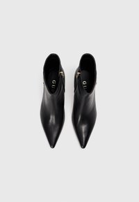 Černé kožené kotníkové polovysoké boty s špičatou špičkou, se zapínáním na zip na boku a lesklým povrchem. Minimalistický design s elegantní siluetou.