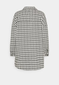 Tweedjacka med ett svart och vitt rutmönster, långa ärmar och krage. Har en något lös passform och detalj i sömmen på baksidan.