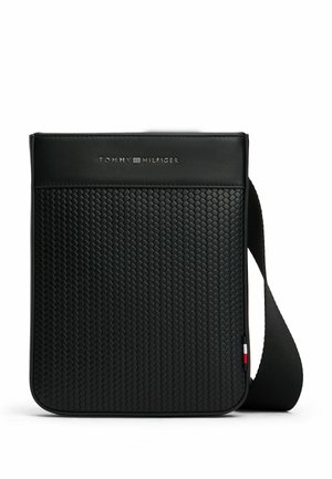 Zwarte gestructureerde crossbodytas met geweven patroon, zwarte band en zilveren Tommy Hilfiger-logo bovenaan in het midden.