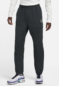 Pantalones cargo negros hechos de material ligero, con una cintura elástica, bolsillos laterales y un bolsillo con cremallera en el muslo.