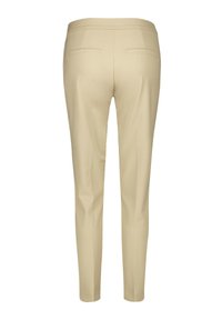 Beżowe spodnie o dopasowanym kroju, z dwiema tylnymi kieszeniami i gładką fakturą. Nogawki zwężają się ku kostce.