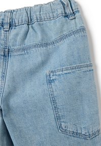 Pantalones de mezclilla de color azul claro con una cinturilla elástica, costuras visibles y un bolsillo trasero único sin ningún adorno adicional.