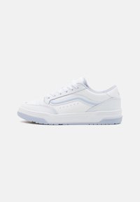 White low-top sneaker with lace-up front, subtle wave design on side, and textured sole against plain white background.