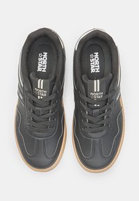 Black athletic shoes with a textured synthetic upper, lace-up design, white and grey accents, and a gum rubber outsole.