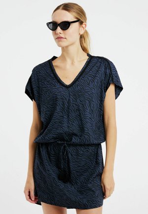 Marineblauwe jurk met een zebraprint, voorzien van een V-hals, korte mouwen en een coulisse taille met een zwart kwastje. Soepele stoftextuur.
