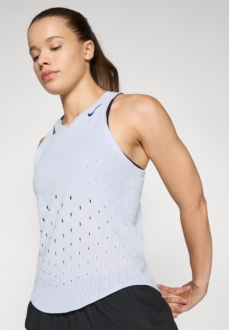 Lichtblauw mouwloos sporttop met perforpatroon, ronde halslijn en subtiel logo. De stof lijkt glad met een lichte glans.