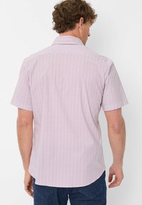 Camicia a maniche corte di colore rosa chiaro con un piccolo motivo geometrico; presenta un colletto classico e un orlo dritto. Tessuto morbido al tatto.