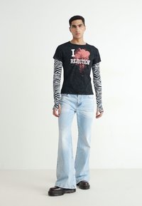 Must musta t-särk musta kastiga "I REJECTION" tekstiga, kihiliselt musta ja valge triibulise pika varrukaga särk. Hele sinine laienev teksapüks ja mustad jalanõud.