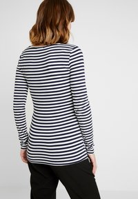 Marinblå och vitrandig långärmad topp med rund Halsringning, slim fit och mjukt bomullstyg. Har en rundad nederkant bak.