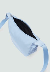 Lichtblauwe stoffen schoudertas met een rits bovenaan, verstelbare schouderband en een gladde textuur. Binnenin is de tas zwart en heeft een eenvoudig ontwerp.