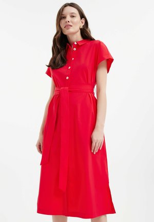Red, short-sleeved dress with a collar, button front, and waist tie. Midi length with side slits. Smooth fabric and tailored design.