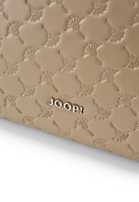 Borsa a mano beige con rilievo che presenta un motivo testurizzato di fiori stilizzati e il logo argento "JOOP!" in evidenza.
