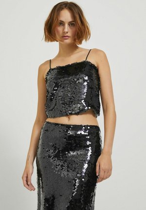 Ensemble deux pièces en sequins noirs comprenant un crop top à fines bretelles et une jupe ajustée assortie, tous deux couverts de sequins brillants.