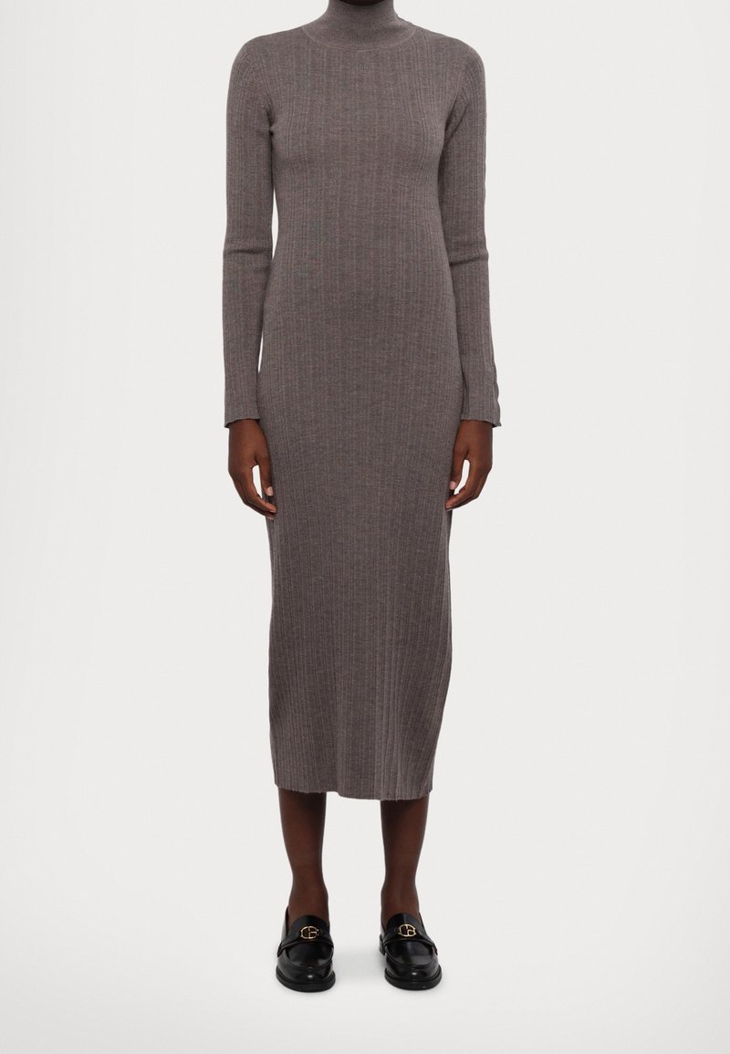 Robe midi à manches longues en maille côtelée taupe portée avec des mocassins en cuir noir ornés de boucles dorées.