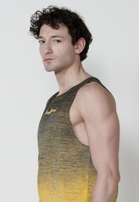 Svetlo siv in rumen gradient majica brez rokavov, lahka tkanina, zaobljen ovratnik in subtilen logotip na prsih.