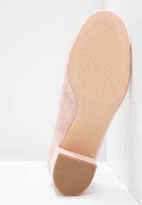 Světle růžové suede vysoké podpatky s texturovanou gumovou podrážkou. Mají čtveratou špičku a skromnou výšku podpatku, na podrážce je minimální branding.