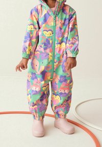 Kolorowy kombinezon przeciwdeszczowy z zabawnym wzorem zwierząt i kwiatów, wykonany z wodoodpornego materiału. Posiada zamek z przodu i elastyczne mankiety.