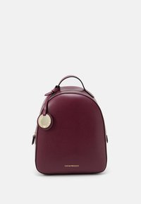 Ryggsäck i bordeauxläder med rundad form, strukturerad yta, topphandtag, guldfärgade beslag och en cirkulär logotypbricka. Dragkedja upptill.