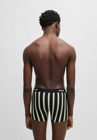 Schwarz-grün gestreifte Boxer-Shorts aus weichem Stoff, mit einem Markenbund. Sichtbare Nähte und das enganliegende Design erhöhen den Tragekomfort.
