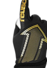 Guante negro con tejido texturizado, que presenta detalles dorados y un patrón de flechas. El nombre de la marca "Reusch" se muestra de manera destacada en dorado.