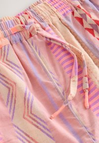 Short en tissu à motifs rose, violet et rouge avec une taille élastique et un cordon noué à l'avant.