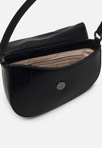 Sac à main noir en matériau synthétique texturé, doté d'une poche intérieure zippée et d'une fermeture à pression.